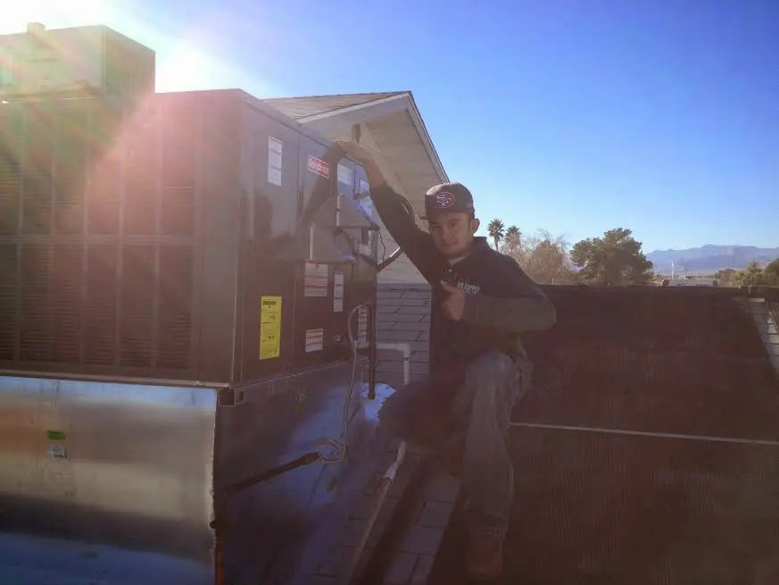 HVAC technician performing AC Tune-Up on a rooftop unit in Camillus